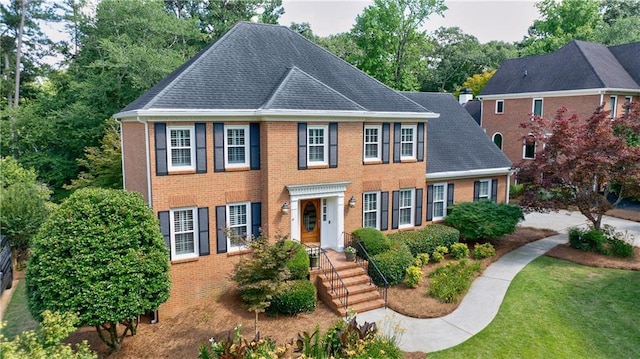 5004 Haralson Way SW, Lilburn, GA 30047 - colonial-style house with brick siding, a front lawn, roof with shingles, and view of scattered trees