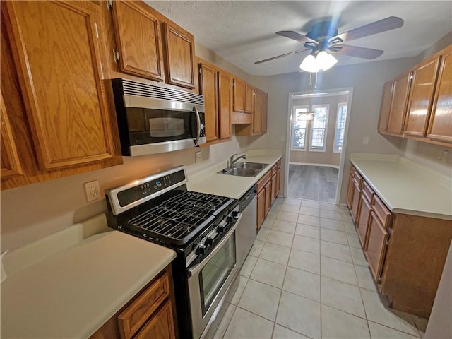 kitchen with ceiling fan, sink, light tile patterned floors, and stainless steel appliances