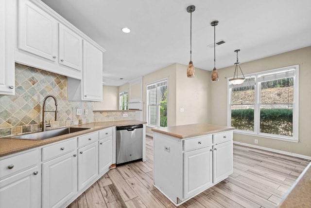 kitchen featuring light wood-style flooring, dishwasher, white cabinetry, and a sink