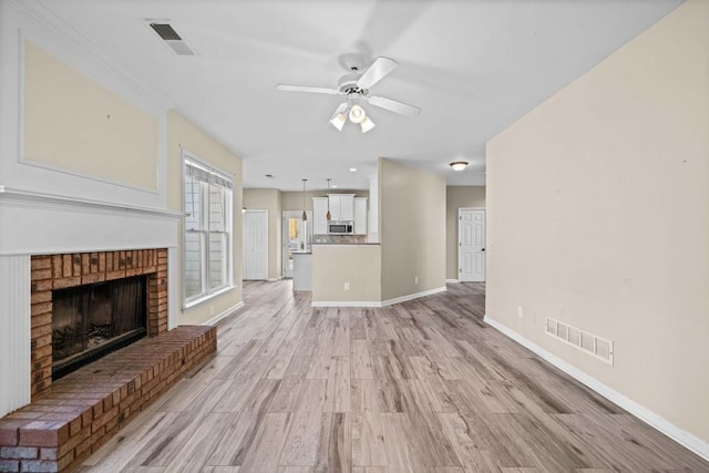 unfurnished living room with ceiling fan, baseboards, visible vents, and light wood-type flooring