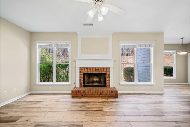 unfurnished living room with a ceiling fan, visible vents, and light wood finished floors