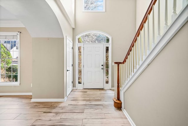 foyer with a high ceiling, stairs, baseboards, and wood finished floors