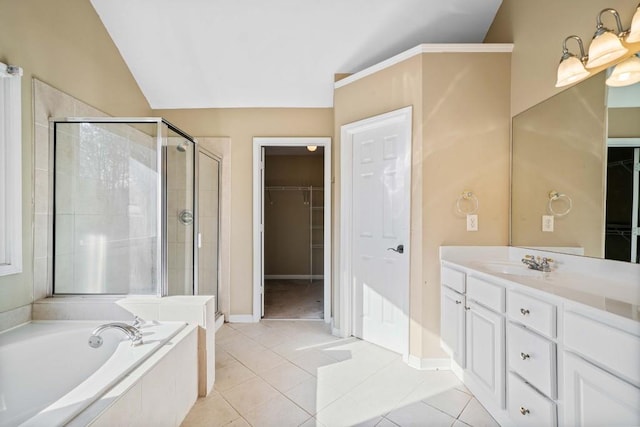 bathroom with vanity, a shower stall, a walk in closet, a garden tub, and tile patterned floors