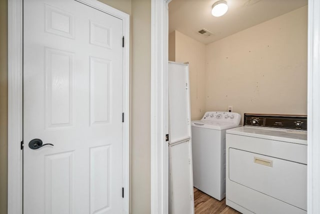 laundry area with laundry area, visible vents, independent washer and dryer, and light wood-type flooring