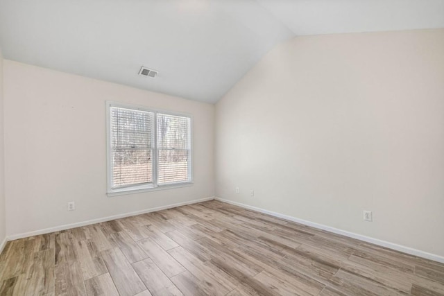 empty room featuring visible vents, baseboards, lofted ceiling, and wood finished floors