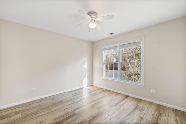 spare room featuring a ceiling fan, wood finished floors, visible vents, and baseboards