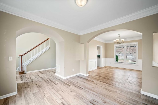 interior space with a chandelier, stairway, ornamental molding, wainscoting, and wood finished floors