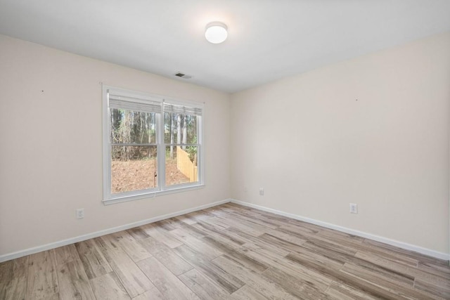 empty room featuring light wood-type flooring, visible vents, and baseboards