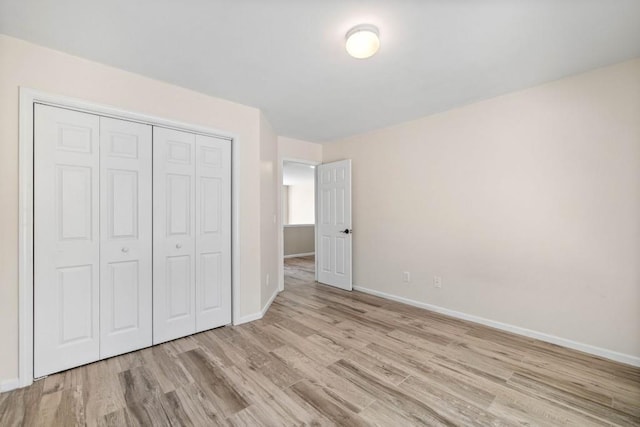 unfurnished bedroom featuring a closet, baseboards, and wood finished floors