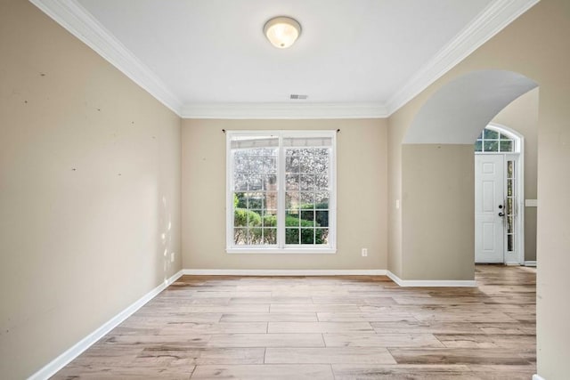 spare room featuring baseboards, arched walkways, wood finished floors, and crown molding