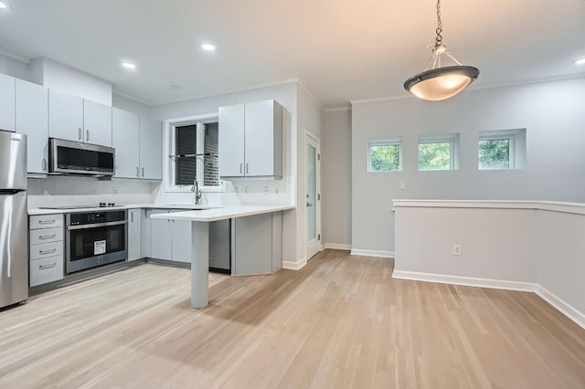 kitchen with kitchen peninsula, sink, light wood-type flooring, and stainless steel appliances