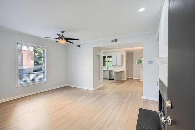 unfurnished living room featuring ceiling fan, light wood-type flooring, and crown molding