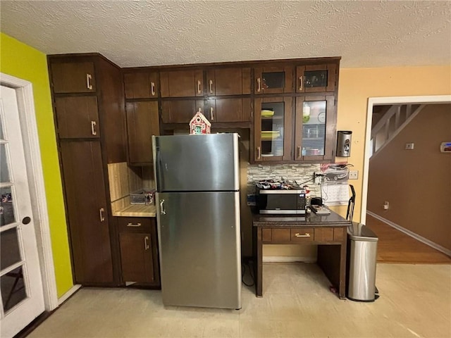 kitchen featuring decorative backsplash, dark brown cabinets, a textured ceiling, and stainless steel appliances