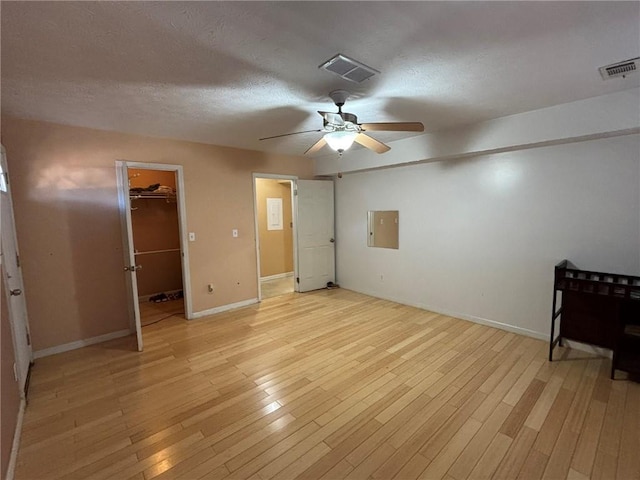 unfurnished bedroom featuring ceiling fan, a spacious closet, a closet, and light hardwood / wood-style flooring