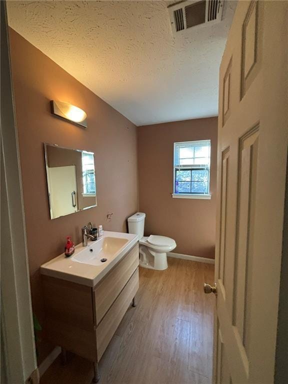 bathroom with wood-type flooring, toilet, vanity, and a textured ceiling