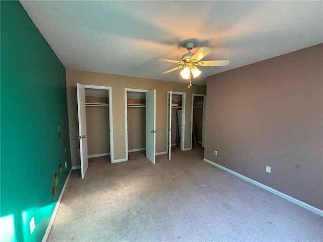 unfurnished bedroom featuring ceiling fan, light carpet, and multiple closets