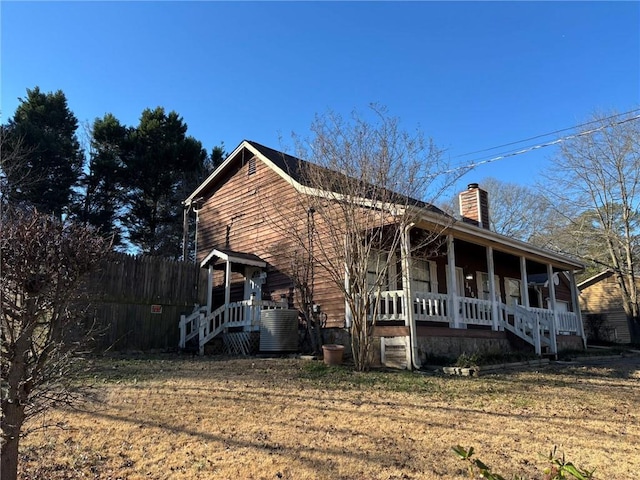 view of front facade with central air condition unit, covered porch, and a front lawn