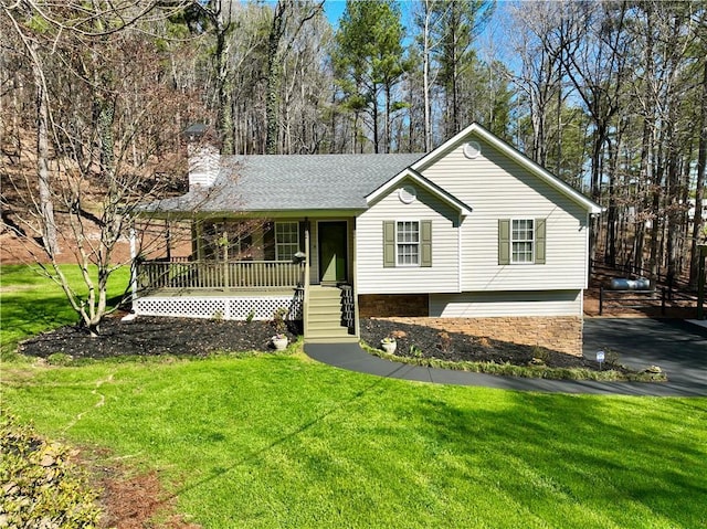 view of front of property featuring a chimney, covered porch, a front yard, and a shingled roof