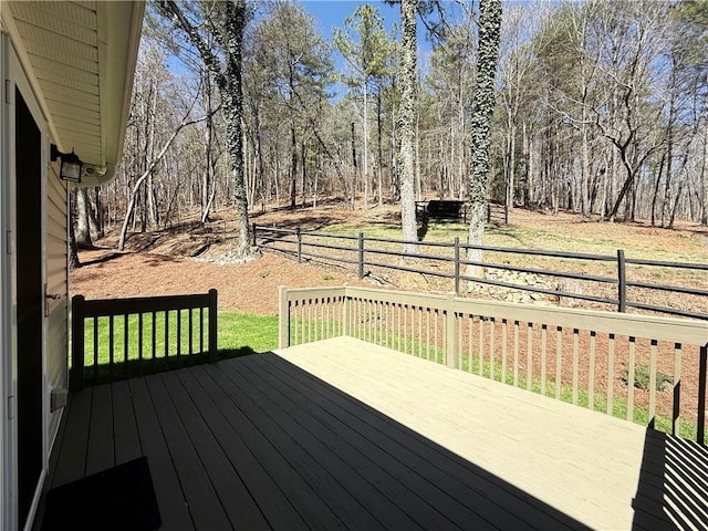 wooden deck featuring a forest view and fence