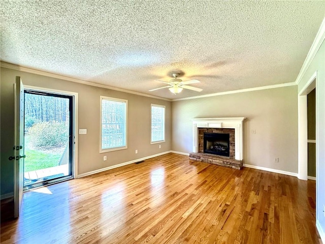 unfurnished living room featuring a ceiling fan, wood finished floors, visible vents, a fireplace, and ornamental molding