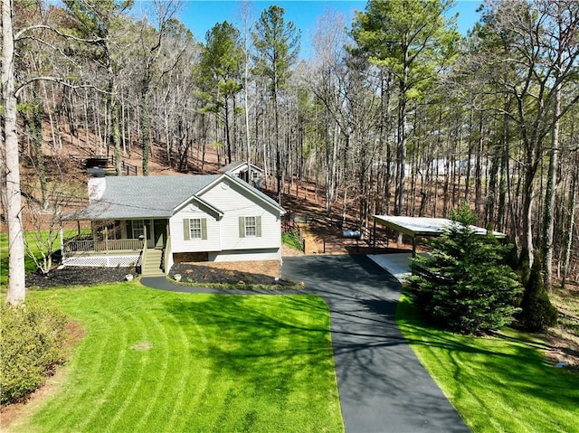 view of front of property with a porch, aphalt driveway, a front yard, and a chimney