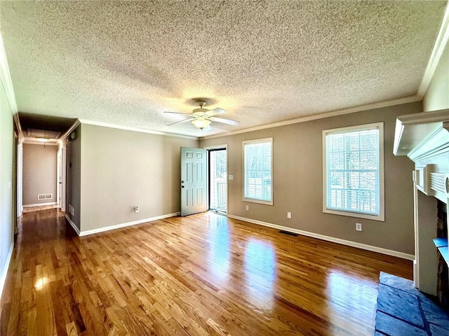 interior space featuring visible vents, a fireplace with raised hearth, crown molding, and wood finished floors