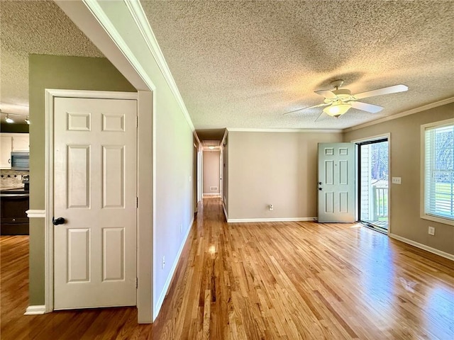 interior space with light wood-style floors, ornamental molding, a ceiling fan, and a textured ceiling