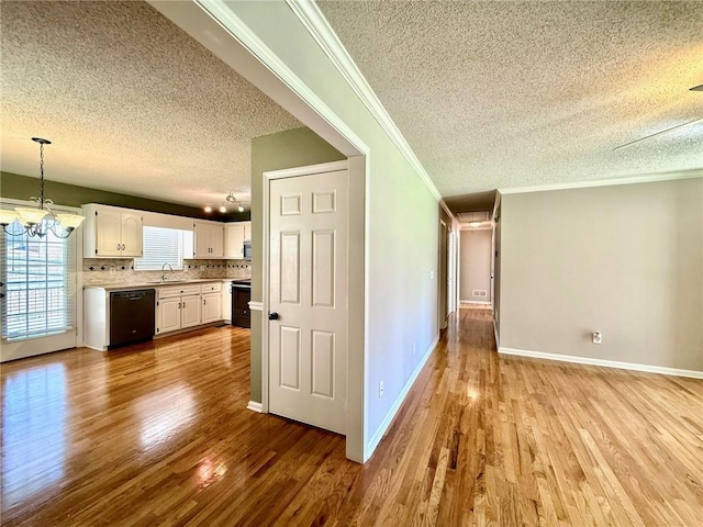 interior space featuring wood finished floors, a sink, black appliances, white cabinets, and a notable chandelier