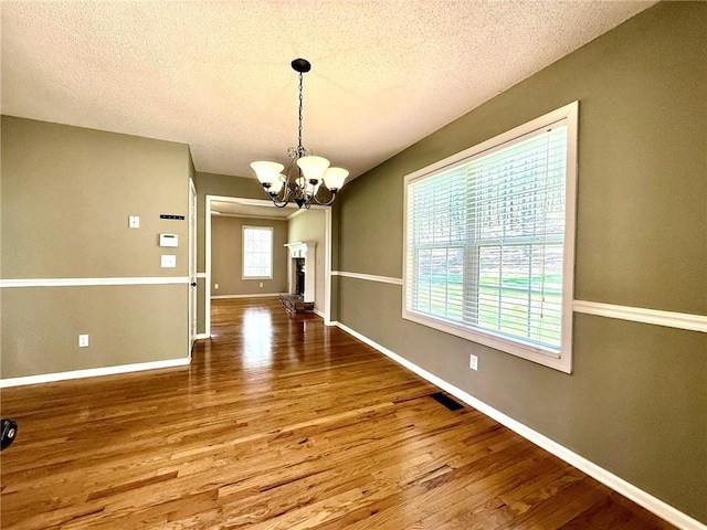 unfurnished dining area featuring a notable chandelier, wood finished floors, baseboards, and a wealth of natural light