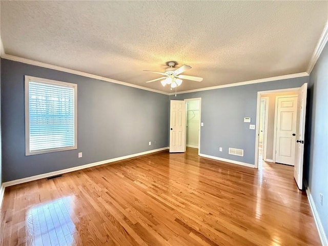 unfurnished bedroom with visible vents, light wood-style flooring, and crown molding