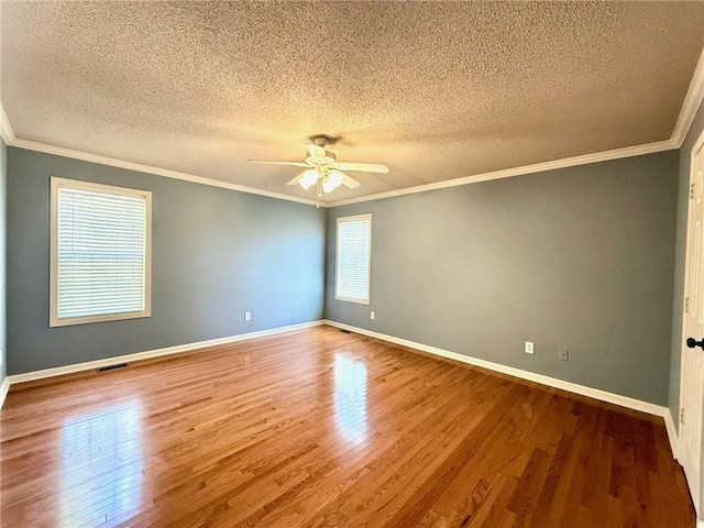 empty room featuring visible vents, ornamental molding, and wood finished floors