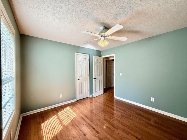 unfurnished bedroom featuring ceiling fan, wood finished floors, baseboards, and a textured ceiling