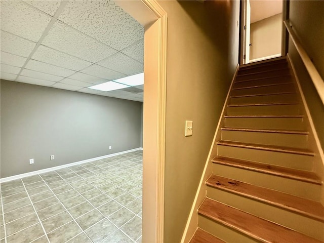 stairs with a drop ceiling and baseboards