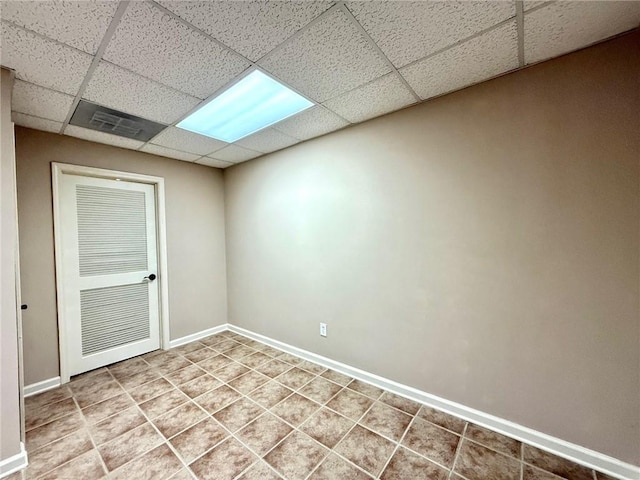 tiled empty room featuring visible vents, a paneled ceiling, and baseboards