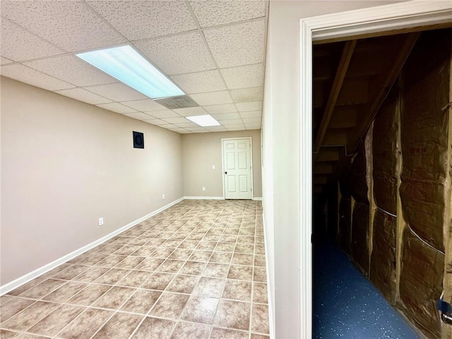 finished below grade area featuring a drop ceiling, baseboards, and tile patterned flooring