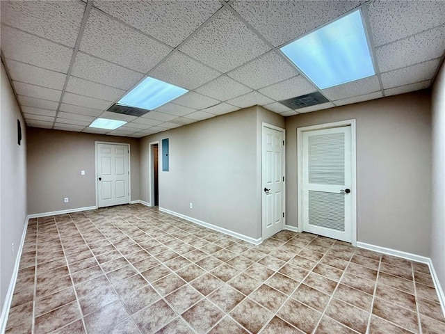 below grade area with tile patterned flooring, a paneled ceiling, and baseboards