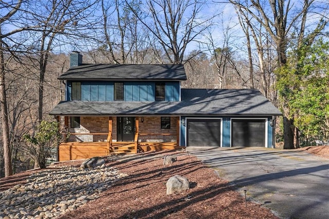 chalet / cabin featuring a porch, driveway, a chimney, and a garage