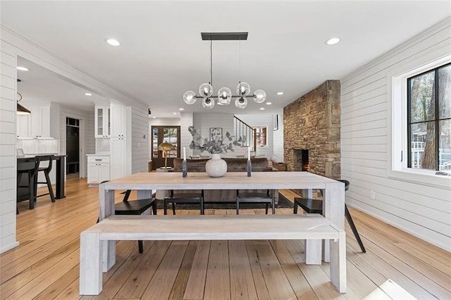 dining area featuring recessed lighting, a fireplace, light wood-style flooring, and an inviting chandelier