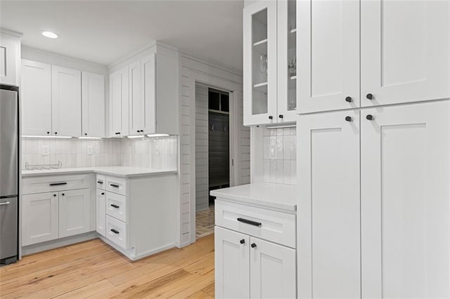 kitchen featuring light wood-style flooring, white cabinetry, light countertops, and freestanding refrigerator