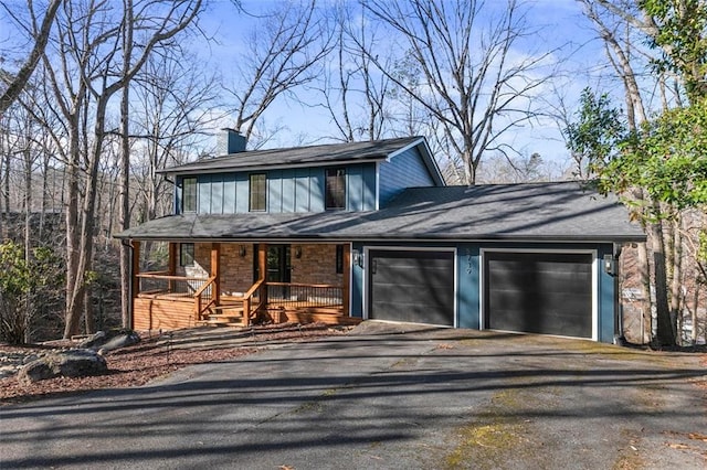 view of front of property featuring a garage, covered porch, a chimney, and aphalt driveway