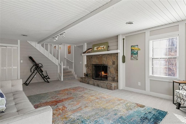 living area with a fireplace, carpet flooring, baseboards, stairs, and beamed ceiling