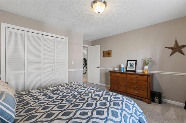 bedroom with a closet, carpet flooring, a textured ceiling, and baseboards