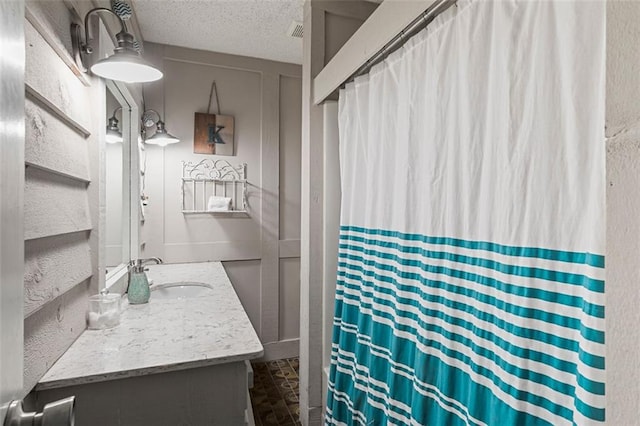 full bath featuring curtained shower, visible vents, a textured ceiling, and vanity