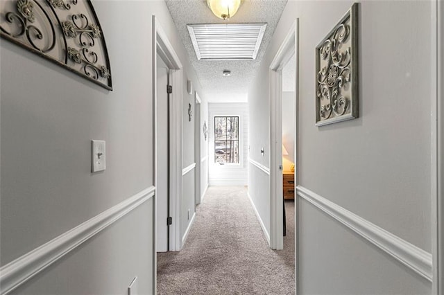 hall with carpet, visible vents, and a textured ceiling