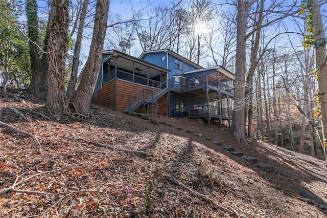 rear view of house with stairway, a wooden deck, and a sunroom