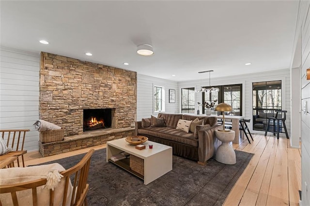 living area with recessed lighting, wood-type flooring, a wealth of natural light, and a stone fireplace