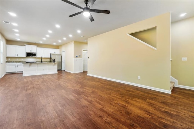 unfurnished living room with ceiling fan, sink, and hardwood / wood-style floors