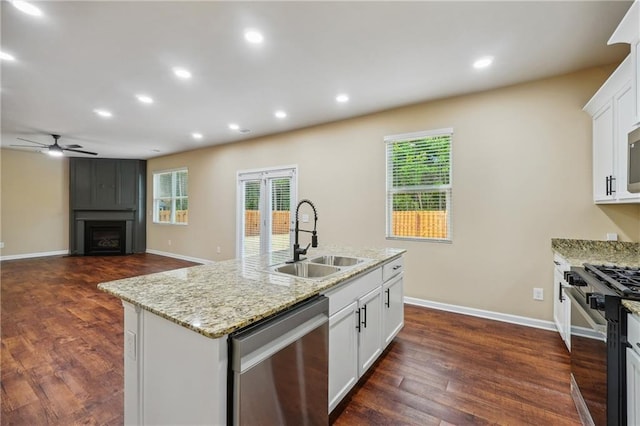 kitchen featuring white cabinets, appliances with stainless steel finishes, a fireplace, sink, and a kitchen island with sink