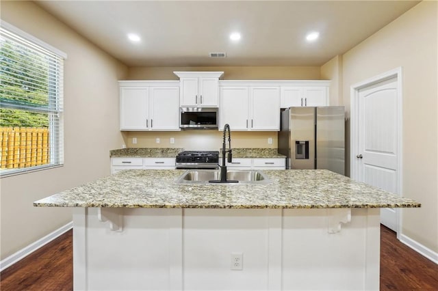 kitchen featuring white cabinets, sink, stainless steel appliances, and a center island with sink