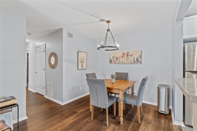 dining space with an inviting chandelier, baseboards, visible vents, and wood finished floors